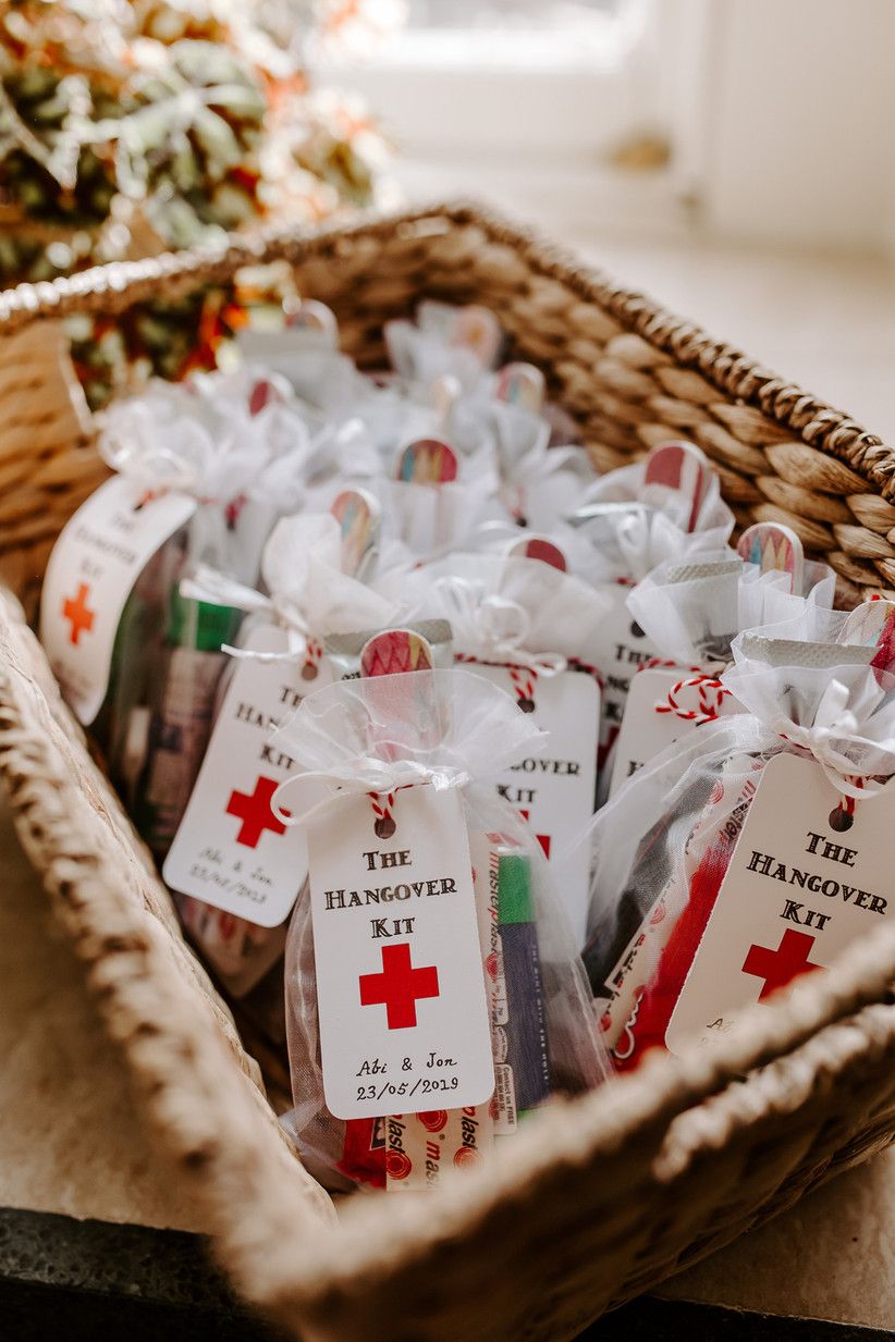 A wicker basket filled with white hanging tags with red strings and hangover kit text, presumably as a gift for a bridal shower or wedding.
