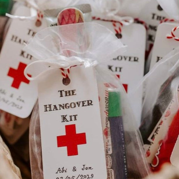 Hangover kits with red cross symbols and personalized tags in a basket.